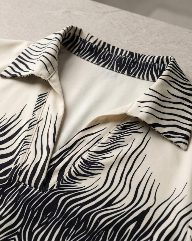 Детайл отблизо на официална бежова макси риза с черен абстрактен принт и елегантно остро деколте с класическа якичка.