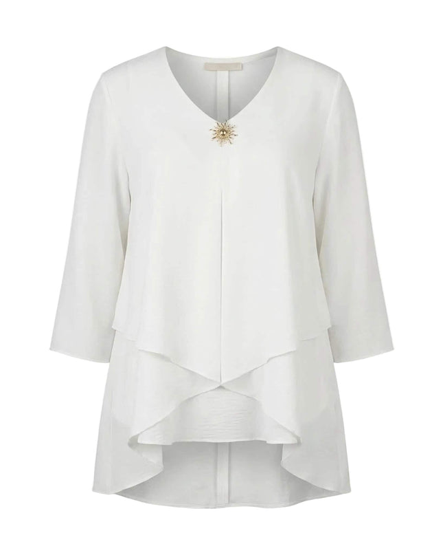 Официална бяла макси туника с асиметрична кройка и брошка, заснета на бял фон.
