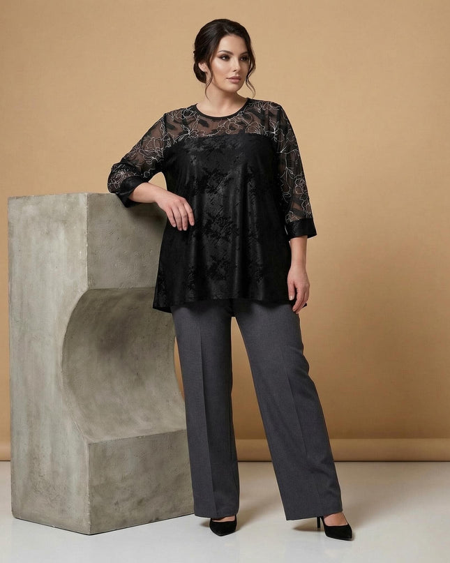 Дамска официална черна туника с прозрачни ръкави и флорална бродерия, представена в цял ръст, съчетана с елегантен сив панталон.