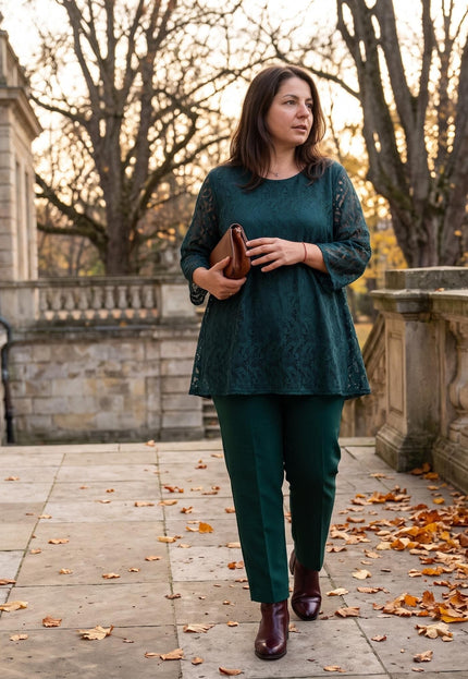 Елегантна дамска официална дантелена туника в тъмнозелен цвят с тричетвърт ръкави, съчетана с панталон в цял ръст сред есенен парк.