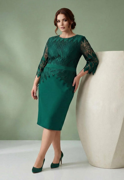 Елегантна официална макси рокля в масленозелен цвят с дантела в горната част, заснета в цял ръст до бяла ваза.