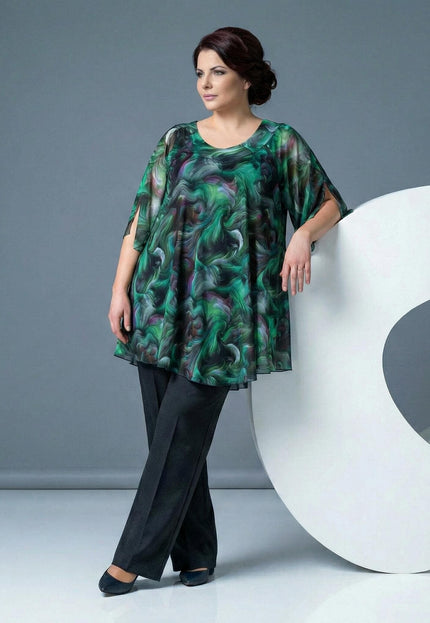 Официална разкроена макси туника с абстрактен принт в зелени нюанси, представена от модел в цял ръст до бял декоративен елемент.