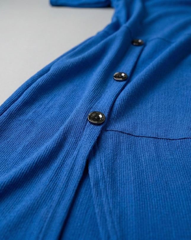 Детайл отблизо на официална рокля в кобалтово синьо, показващ текстурираната материя и декоративните метални копчета.