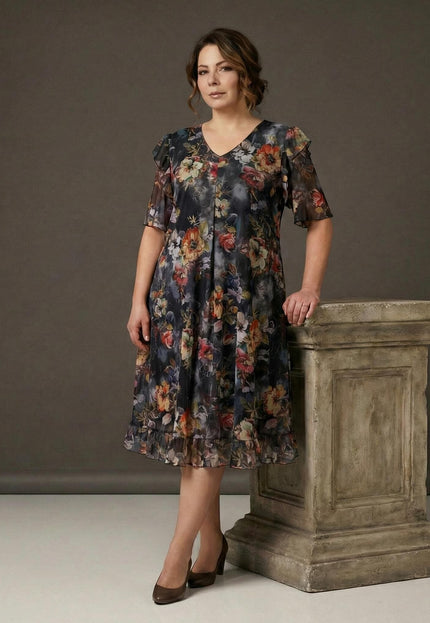 Официална разкроена рокля от шифон с живописен флорален принт, V-образно деколте и волан, заснета в цял ръст до декоративна колона.