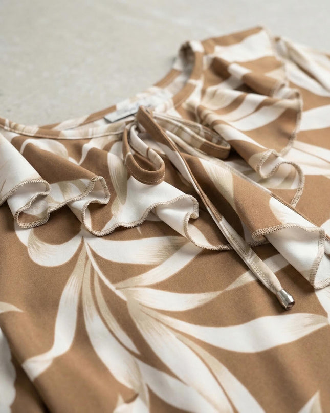 Детайл отблизо на официална туника в светлокафяво с бели листа, показващ ефектното деколте с къдрички и връзки с метални накрайници.