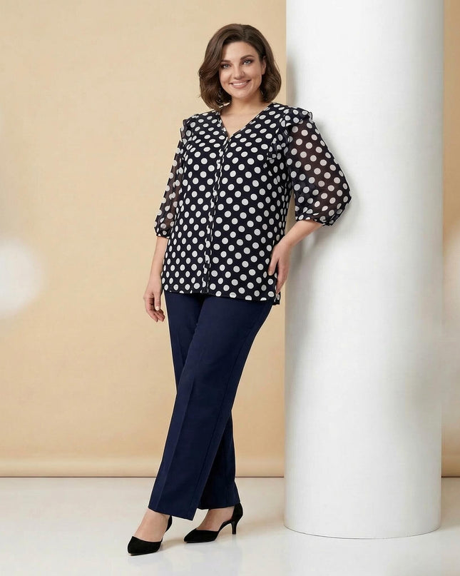 Официална тъмносиня туника на бели точки с 3/4 ефирни ръкави, представена на модел в цял ръст до бяла колона.
