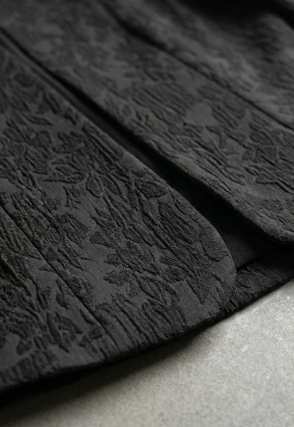 Детайл отблизо на ефектната релефна текстура и долния ръб на официално черно сако големи размери, показващ качеството на изработка.