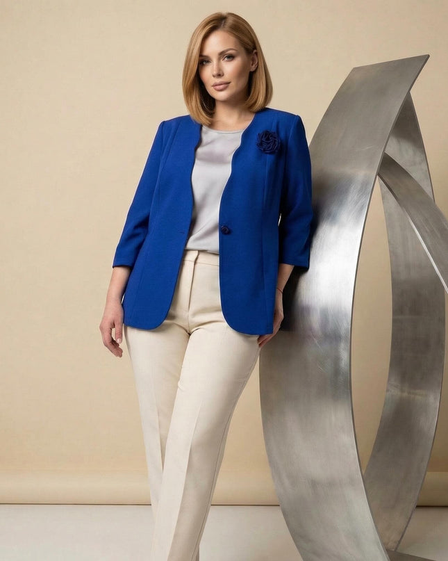 3/4 кадър на модел с официално дамско сако в кралскосин цвят с декоративна роза. Елегантна визия, съчетана със светъл панталон и топ.