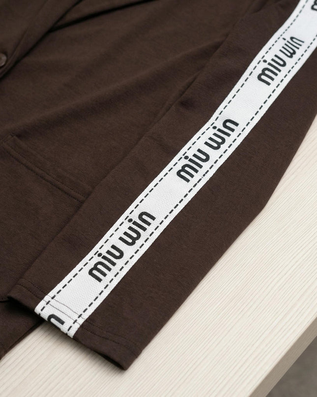 Детайлна снимка на ръкава на кафяв дамски комплект, акцентираща върху декоративната бяла лента с надпис miu win и текстурата на плата.