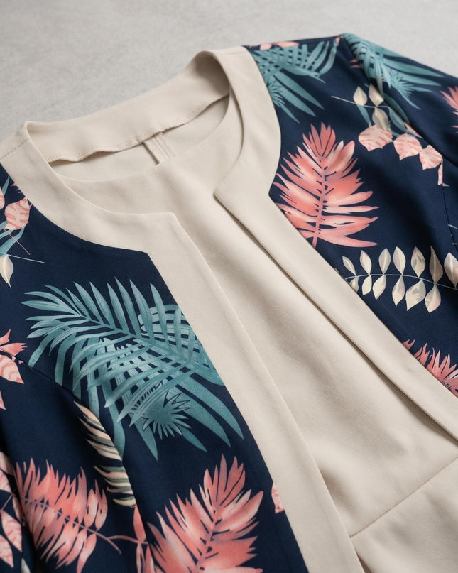 Детайл отблизо на елегантен комплект голям размер - тъмносиньо сако с розов и зелен флорален десен и светлобежова рокля, показващ материята и кройката на деколтето.