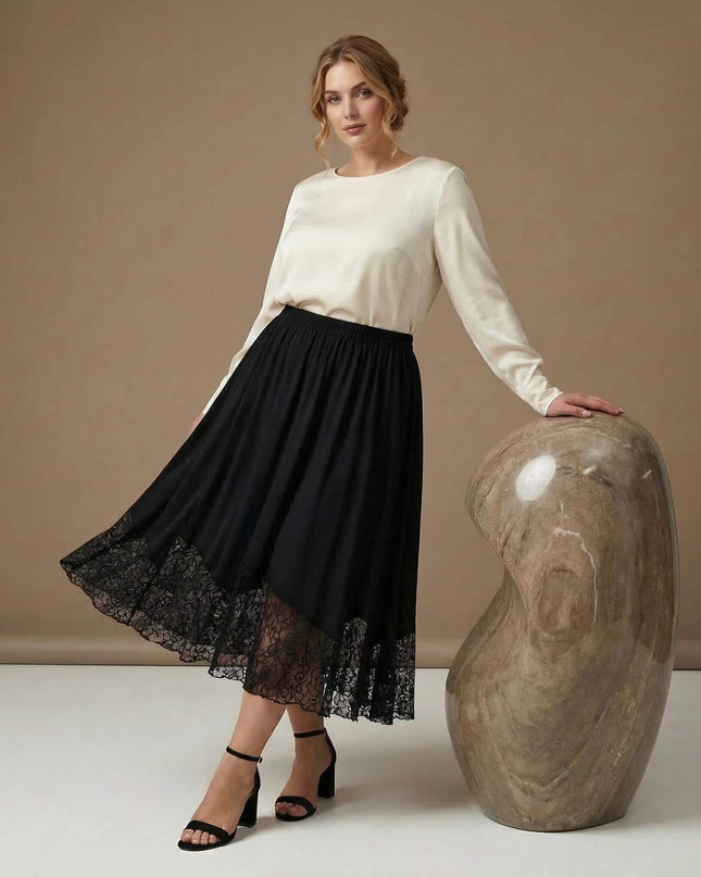 Черна макси пола с разкроен силует и широк панел от флорална дантела. Показана в цял ръст върху модел, съчетана с бяла блуза на бежов фон.