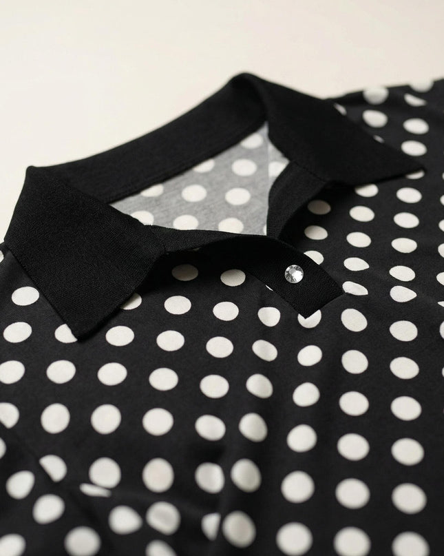 Детайл отблизо на черна макси туника, показващ елегантната яка, прозрачното декоративно копче и десена на бели точки.