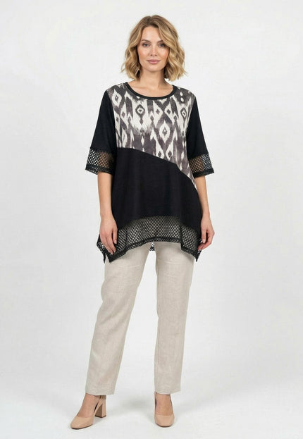 Официална черна макси туника с абстрактен принт, асиметрична кройка и мрежести детайли, представена в цял ръст на бял фон с бежов панталон.