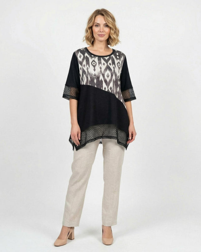 Официална черна макси туника с абстрактен принт, асиметрична кройка и мрежести детайли, представена в цял ръст на бял фон с бежов панталон.