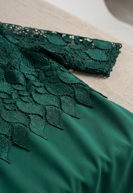 Детайлен кадър на официална макси рокля в масленозелен цвят, показващ отблизо красивата дантела с мотиви на листа в горната част.