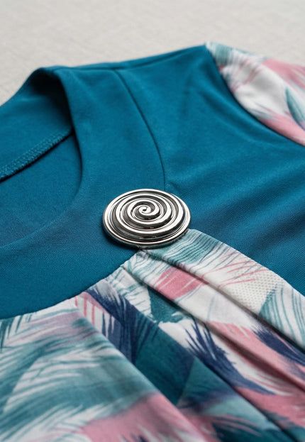 Детайл отблизо на деколте с елегантна сребриста брошка върху официална макси туника в цвят петрол и цветен ефирен шифон.