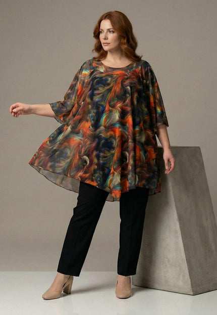 Официална макси туника от шифон с асиметричен дизайн и преливащи нюанси, представена в цял ръст върху модел с черни панталони.