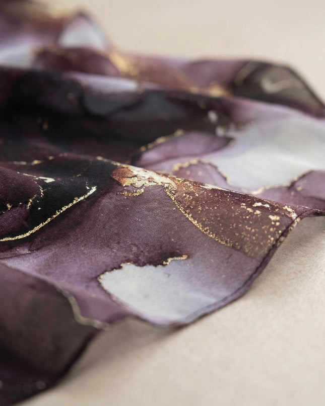 Детайл отблизо на ефирния шифон с абстрактен мраморен принт в лилаво и златни акценти от официална макси туника тип пончо.