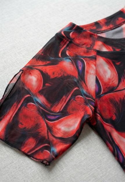 Детайл отблизо на ръкава с цепка и обло деколте на официална макси туника от цветен шифон в червени и черни нюанси.