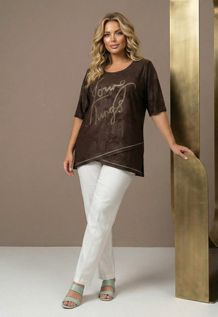 Елегантна кафява макси туника с асиметрична предна част, бял кант и декоративен надпис. Представена в цял ръст върху модел с бял панталон.