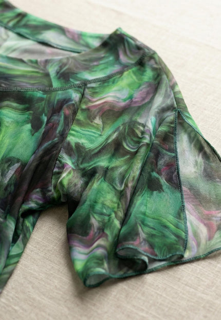 Детайлен кадър на ръкав с ефектна цепка от официална макси туника със зелен абстрактен принт и фина мрежеста материя.