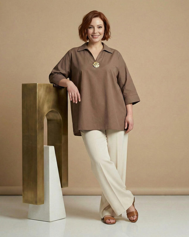 Елегантна разкроена памучна макси риза в цвят мока с декоративен елемент на деколтето, представена в цял ръст върху модел до златист постамент