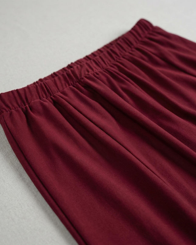 Детайл отблизо на ластичния колан и меките гънки на официална разкроена пола в наситено бордо.