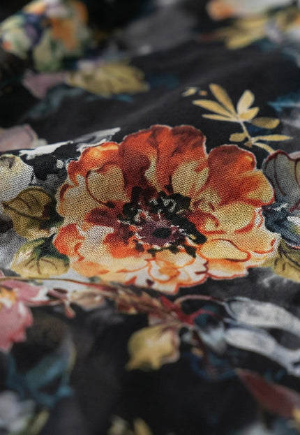 Детайл отблизо на материята на официална разкроена рокля от шифон, разкриващ текстурата на плата и живописния флорален десен с оранжеви цветя.
