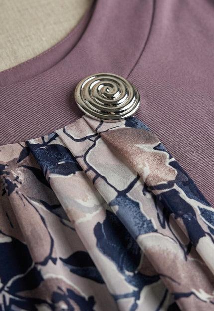 Детайлен кадър на деколтето на официална туника в цвят пепел от рози, акцентиращ върху елегантната сребриста брошка и набрания флорален шифон.