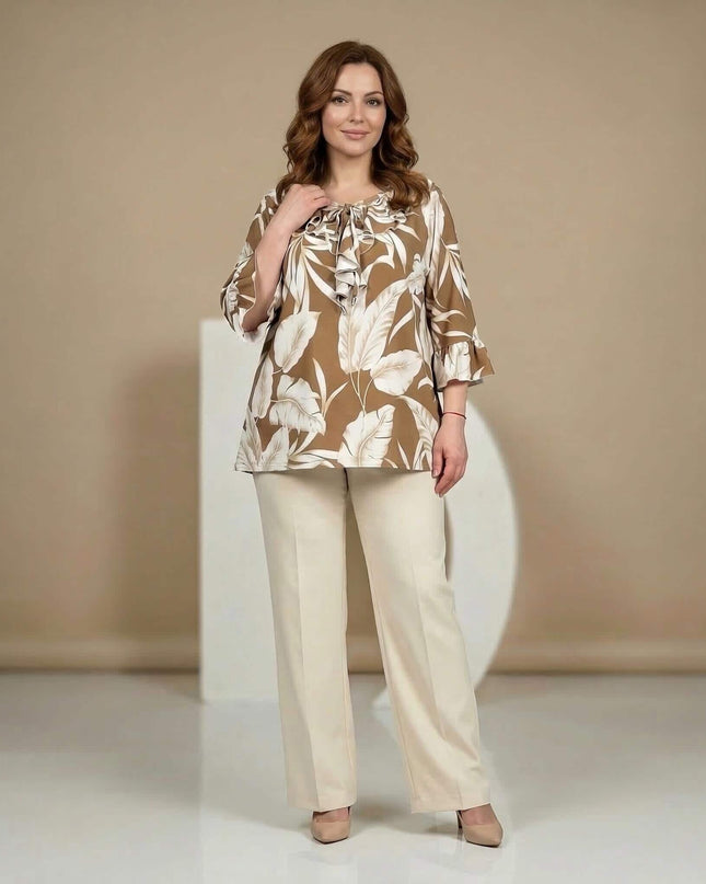 Официална разкроена туника в светлокафяво с принт на бели листа и набрано деколте. Кадър в цял ръст отпред със светъл панталон.