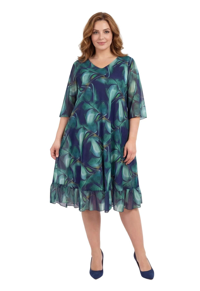 Официална шифонена рокля големи размери с абстрактен десен в сини и зелени тонове, кадър в цял ръст.