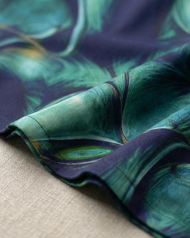Детайл отблизо на материята на официална шифонена рокля, показващ красивия абстрактен десен в преливащи тъмносини и зелени тонове.