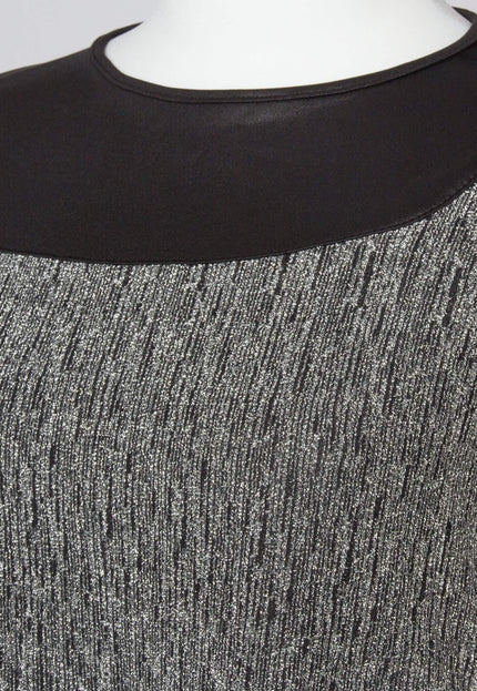 Детайл отблизо на официална сребриста туника, показващ текстурираната материя с блясък и контрастната черна зона около облото деколте.