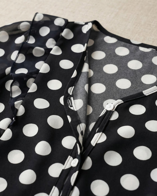 Детайл отблизо на официална тъмносиня туника на бели точки, показващ V-образно деколте и декоративни бели копчета.