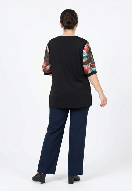 Официална черна туника големи размери, снимана отзад в цял ръст. Моделът е с изчистен гръб и къси ръкави с цветен флорален принт на бял фон.