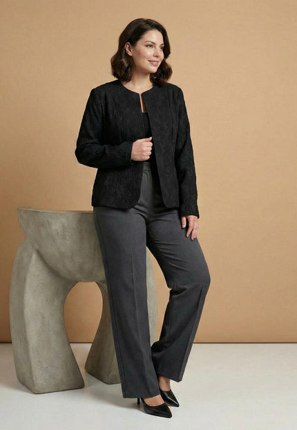 Официално черно сако големи размери с ефектна релефна текстура, представено в цял ръст върху модел, съчетано със сив панталон за завършена делова визия.
