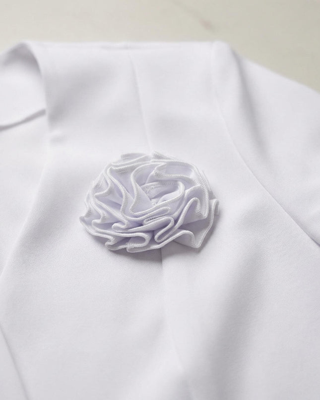 Детайл отблизо на ефектната брошка роза от плат, прикрепена към ревера на официално дамско бяло сако.