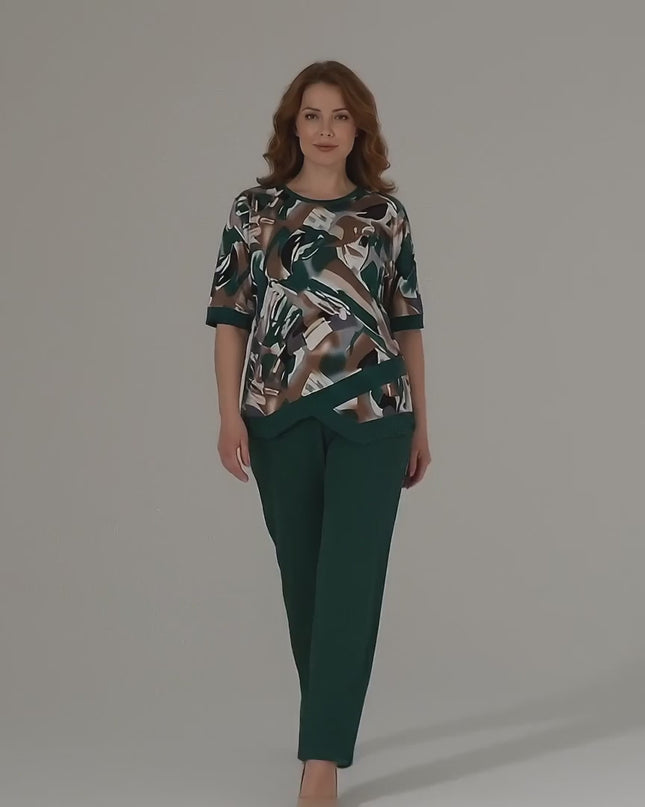 Плюс размер модел върви бавно към камерата в студио с неутрален фон, носейки Официален масленозелен макси комплект туника и панталон