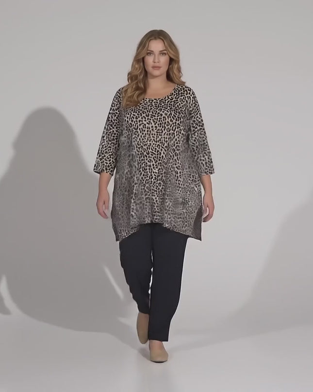 Студийно видео на неутрален фон, в което плюс сайз модел върви бавно към камерата, облечен с Ежедневна макси туника в леопардов десен големи размери