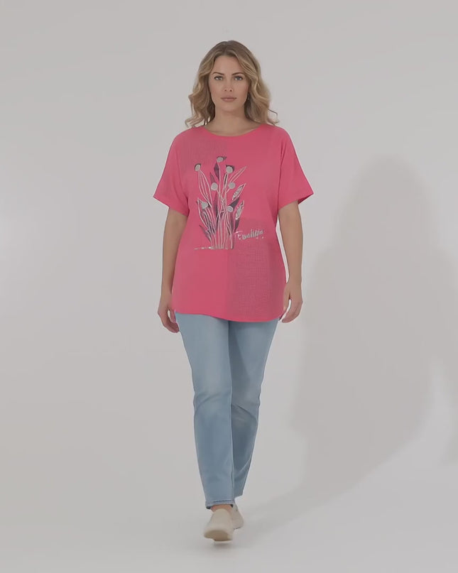 Презентационно видео в студио, показващо плюс сайз модел, който върви бавно към камерата, носейки Дамска лятна туника големи размери с цветя в коралов цвят