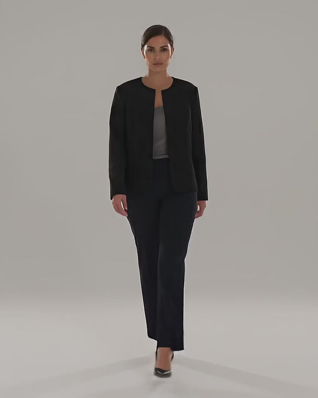 Видео в студио на неутрален фон, в което плюс сайз модел върви бавно към камерата, облечена в Официално черно сако големи размери с ефектна релефна текстура