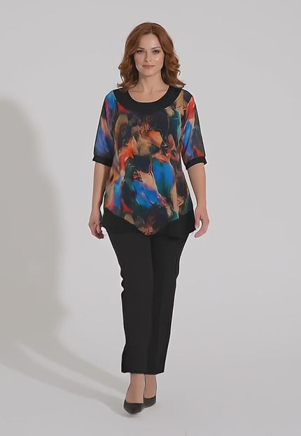 Видео в студийна среда, показващо плюс сайз модел, който върви бавно към камерата, облечен в Официална разкроена туника с асиметричен шифон и цветен принт