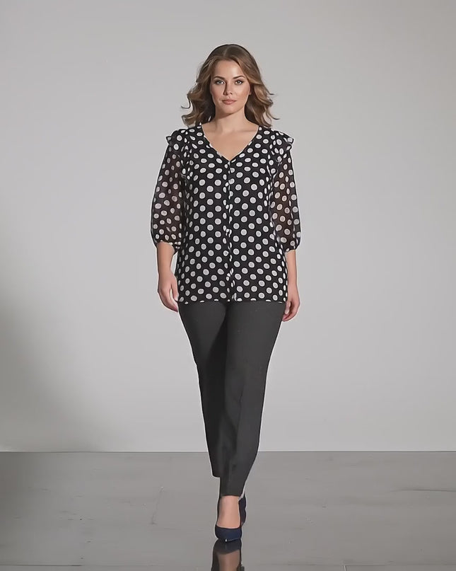 Видео в студийна среда показващо жена модел която се разхожда бавно към камерата и носи Официална тъмносиня туника на бели точки големи размери