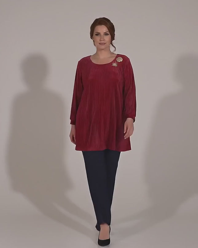 Студийно видео на неутрален фон, в което макси модел върви бавно към камерата, облечена в Елегантна официална макси туника в червено с красиви брошки