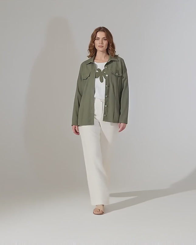 Студийно видео представяне на неутрален фон, в което женски модел плюс размер върви бавно към камерата, облечена в Дамски комплект от две части с тениска с щампа и сако каки