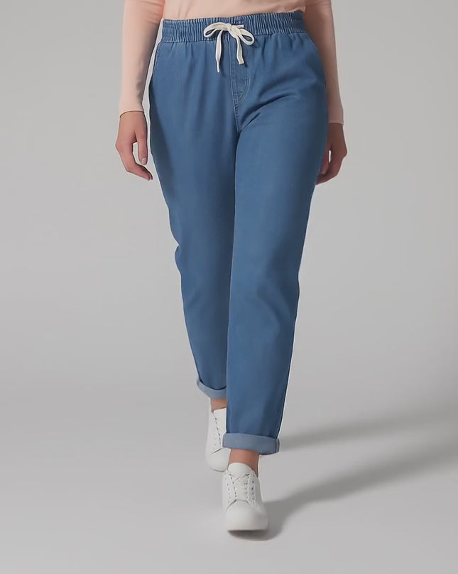 Видео в студио с неутрален фон, на което плюс сайз модел носи Сини летни дънки големи размери с права кройка и върви бавно към камерата