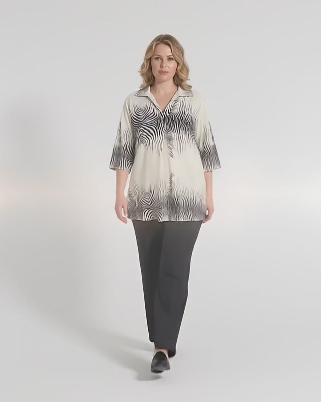 Плюс сайз модел в студийна среда върви бавно към камерата, облечена с Официална бежова макси риза с къс ръкав и остро деколте