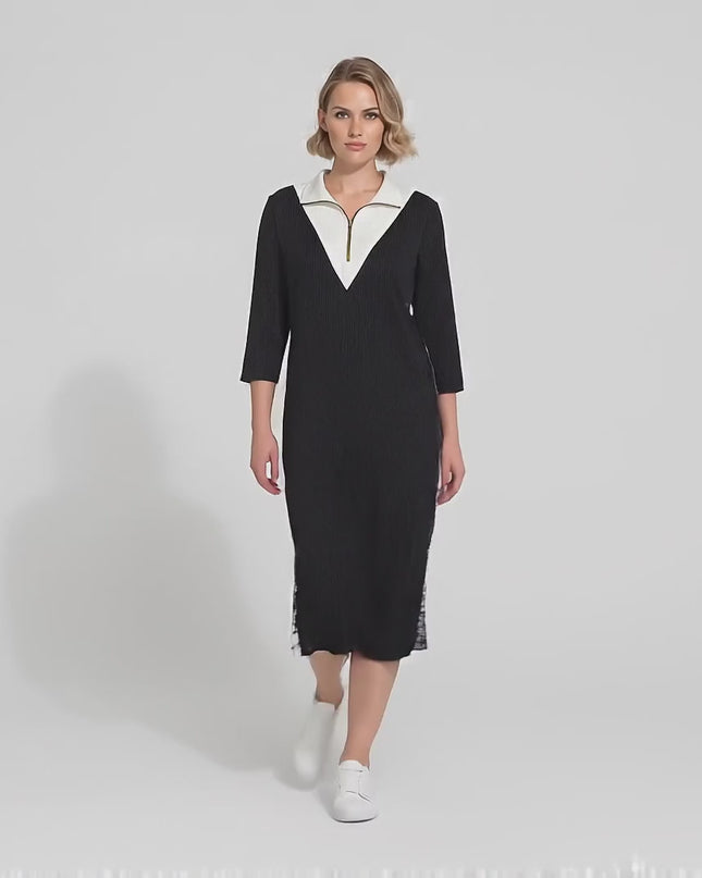 Плюс сайз модел дефилира бавно към камерата в студио на неутрален фон, облечен в Черна спортно елегантна макси рокля с цип и ефектни странични ленти