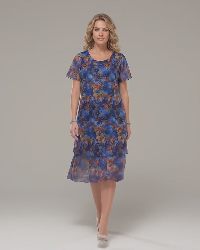 Видео в студийна среда, показващо макси модел, който върви бавно към камерата и носи Официална макси рокля от пъстър шифон с разкроен силует