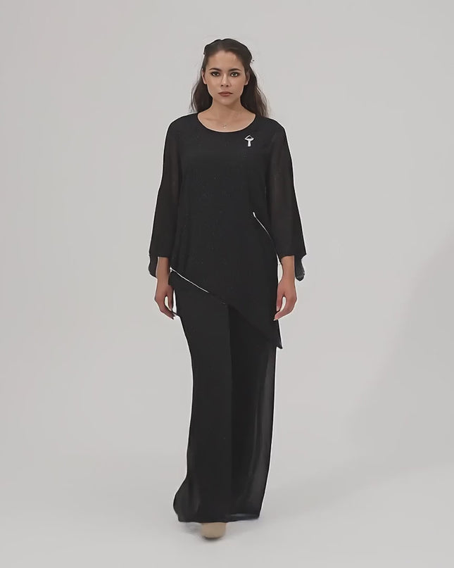 Жена модел върви бавно към камерата в студийна среда с неутрален фон, облечена в Официален костюм от две части в черно в макси размери